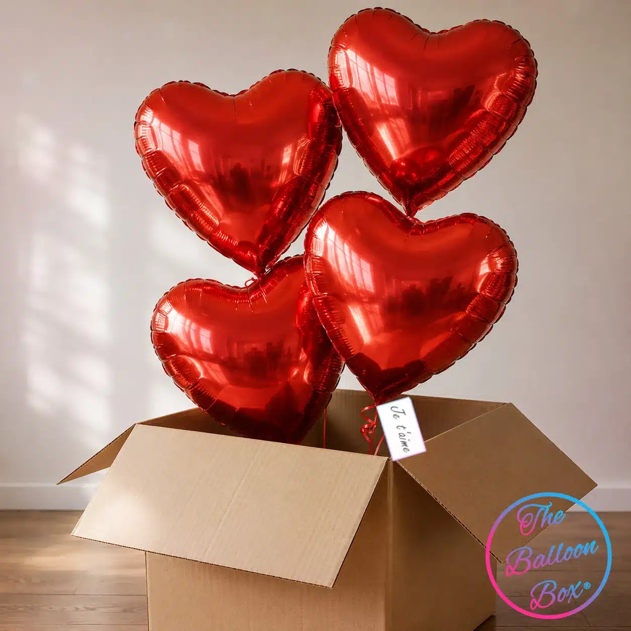 4 ballons gonflés à l'hélium sortants d'une box cadeau en carton accompangés d'une petite carte